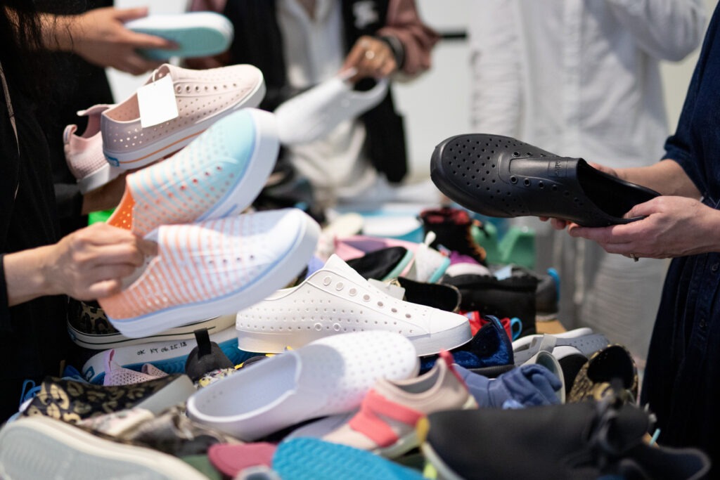 A group of people looking at a pile of shoes.